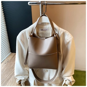 Gros plan du sac seau marron clair avec des surpiqûres blanches et une poche frontale
