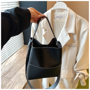 Détail du sac seau noir avec surpiqûres blanches contrastées et poche avant minimaliste