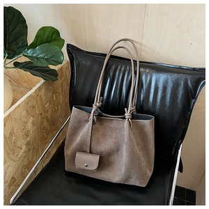 Detail of vintage brown matte tote bag with matching coin purse on a leather chair