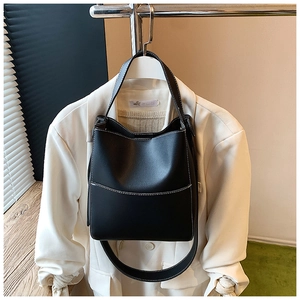 Détail d'un sac seau noir avec coutures blanches contrastées et doubles bandoulières