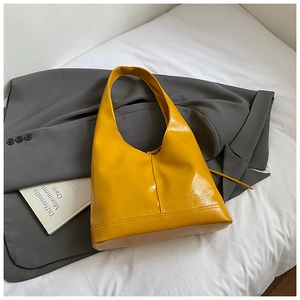 Detailed close-up of glossy bright yellow hobo bag with reflective patent leather texture