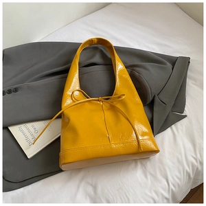 Close-up of bright yellow glossy patent leather tote bag with elegant bow detail