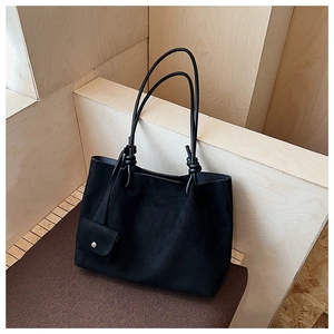 Detail of large black matte tote bag with knotted straps and matching mini pouch
