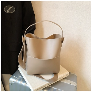 Vue détaillée d'un sac seau en cuir beige avec poche extérieure sur un livre blanc