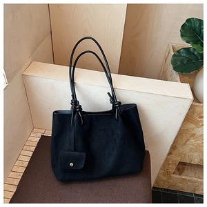 Close-up of black suede tote bag with shoulder straps and detachable pouch detail