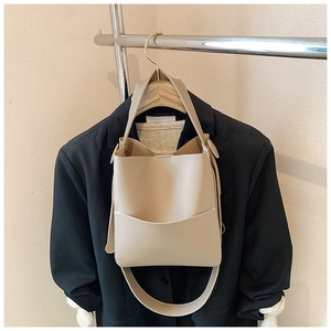 Détail d'un sac seau beige avec texture cuir PU lisse et large bandoulière amovible