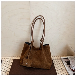Detail of dark brown matte tote bag with shoulder straps and small matching pouch charm