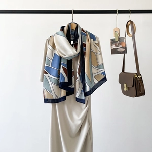Detail view of geometric silk scarf with navy and beige patterns on elegant white dress