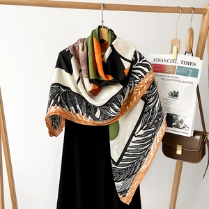 Detail of luxury silk scarf with palm leaf pattern draped on a wooden rack