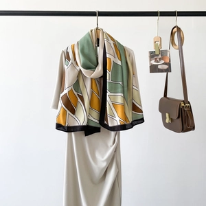 Close-up of silk scarf with herringbone pattern draped over a beige pleated dress