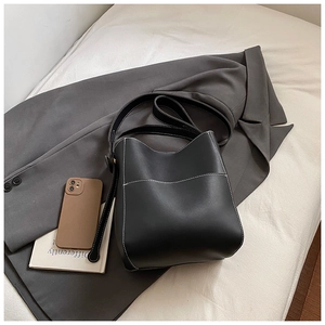 Vue détaillée du sac seau noir avec coutures blanches contrastées et poche externe
