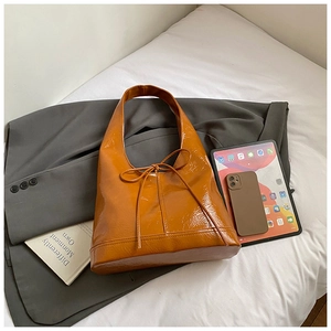 Detail of caramel glossy leather tote bag featuring elegant bow tie and large capacity