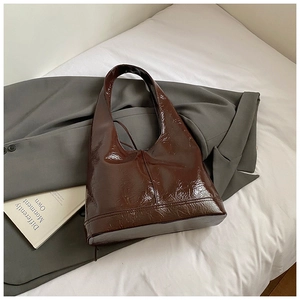 Detail of dark brown glossy patent leather tote bag with rich texture and a wide strap