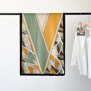 Detail of herringbone pattern silk scarf with yellow and green geometric leaf textures