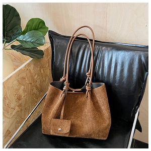 Detailed macro view of vintage brown suede tote bag with knotted straps and matching coin purse