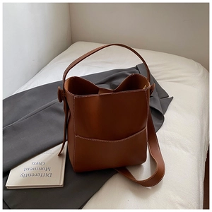 Détail d'un sac seau caramel avec surpiqûres blanches contrastées et poche extérieure