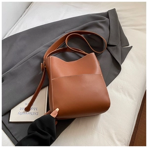 Détail d'un sac seau marron avec des surpiqûres blanches et une poche avant pratique