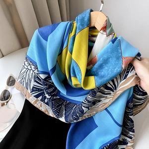 Detail of luxury silk scarf with blue and yellow geometric patterns on wooden hanger