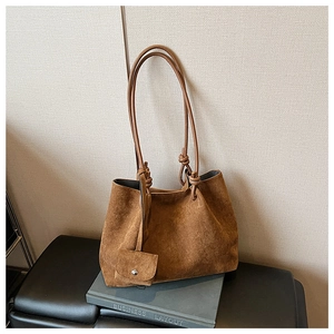 Detail view of dark brown matte suede tote bag with knotted shoulder strap and matching pouch