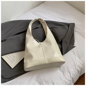 Close-up of the ivory glossy wrinkled patent leather texture and fine vertical stitching on the bag