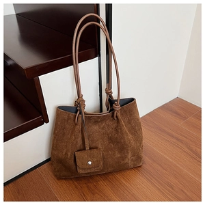 Detail of vintage brown suede tote bag featuring unique knotted handles and a matching mini pouch