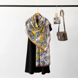 Detailed shot of yellow silk scarf with rose print draped elegantly on a hanger