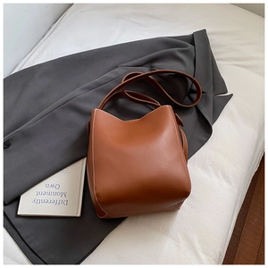 Détail d'un sac seau marron avec surpiqûres blanches sur une veste de costume