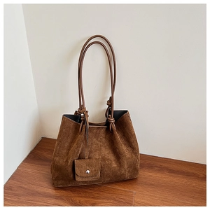 Detail of dark brown matte leather tote bag with knotted straps and hanging coin purse