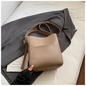 Vue détaillée du sac seau marron clair avec surpiqûres blanches sur veste grise
