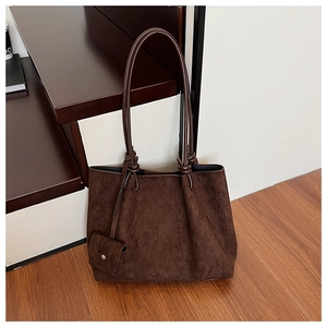Detail of dark brown matte suede tote bag featuring a round silver metal buckle on a small pouch