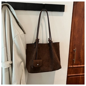 Detail of dark brown matte suede tote bag with decorative knot handles and mini pouch