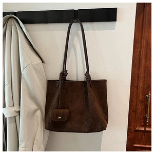 Detail of matte dark brown suede tote bag featuring a decorative knotted shoulder strap