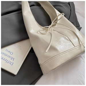 Chic cream bow shoulder bag with glossy crinkled leather finish and sleek minimalist design