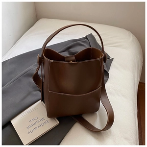 Détail du sac seau marron foncé avec surpiqûres blanches et une poche sur le devant