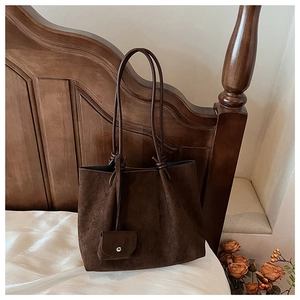 Detail view of large dark brown tote bag with suede texture and hanging mini pouch