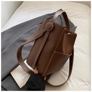 Détail d'un sac seau en cuir marron foncé avec coutures blanches et poche latérale