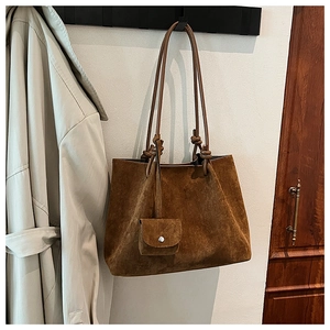 Detail of dark brown matte tote bag with shoulder strap knot and small coin purse charm