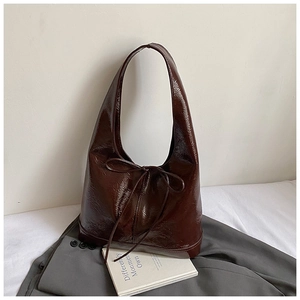 Detail of dark brown glossy tote bag with ribbon bow and wrinkled leather texture