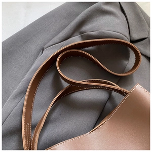 Gros plan de la bandoulière en cuir marron avec coutures contrastées blanches