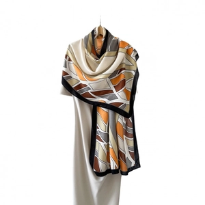 Women's long silk scarf with herringbone pattern and abstract geometric leaf print in orange