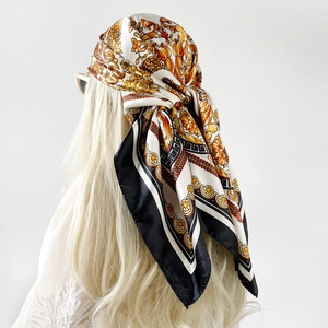 Dettaglio di un foulard in raso barocco vintage con motivi floreali e bordo greco