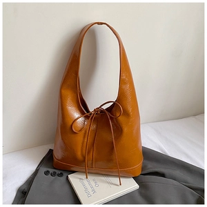 Detailed close-up of a caramel high-gloss shoulder bag with stylish bow tie decoration