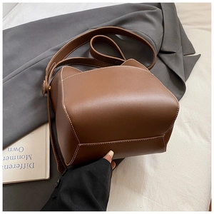 Vue de dessus d'un sac seau marron foncé avec surpiqûres blanches sur blazer gris