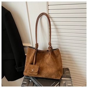 Macro detail of brown matte suede tote bag with knotted shoulder straps and mini pouch