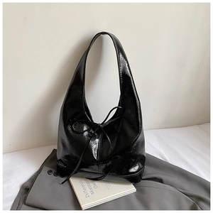 Detail shot of black patent leather hobo bag with bow decoration and glossy finish