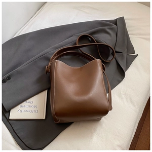 Détail d'un sac seau en cuir marron avec surpiqûres blanches et une bandoulière fine