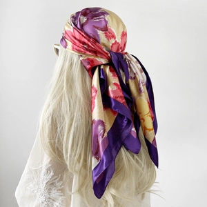 Detailed back view of a woman wearing a silk-like square scarf with floral print as a headscarf