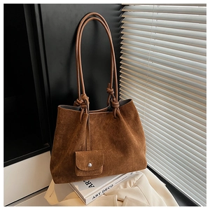 Detail view of brown matte suede tote bag with knotted handles and a matching pouch