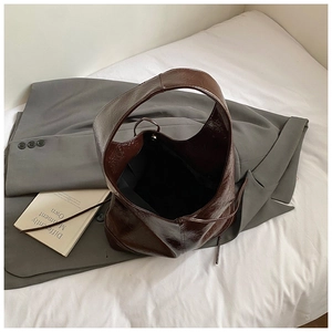 Close-up of a large dark brown patent leather tote bag with stylish strap detail