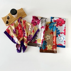 Detailed view of floral satin square scarves in four elegant colors with a glossy silk texture